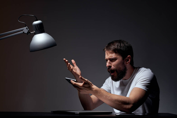 uomo d'affari con telefono cellulare su sfondo scuro e lampada in ferro vista ritagliata del lavoro - Foto, immagini