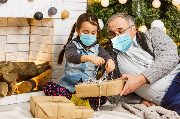 Οικογένεια με προστατευτικές μάσκες σε καραντίνα. Κανονική ζωή με τον κορωνοϊό. Τρόπος ζωής COVID-19. Χριστούγεννα προστασίας ιών καραντίνας - Φωτογραφία, εικόνα