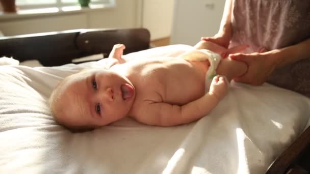 Moeder doet oefeningen voor haar pasgeboren baby - strekt zijn benen - Video