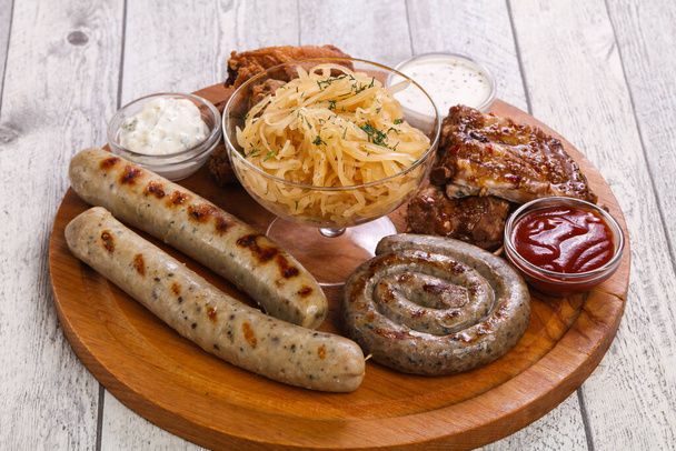 Fleischplatte mit Grillwürsten, Rippchen und Chicken Wings serviert Kohl - Foto, Bild