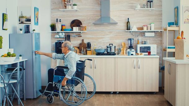 Behinderter Mann öffnet Kühlschrank - Foto, Bild