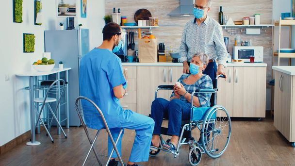 Elderly couple home visit by geriatrician in protective wear - Photo, Image