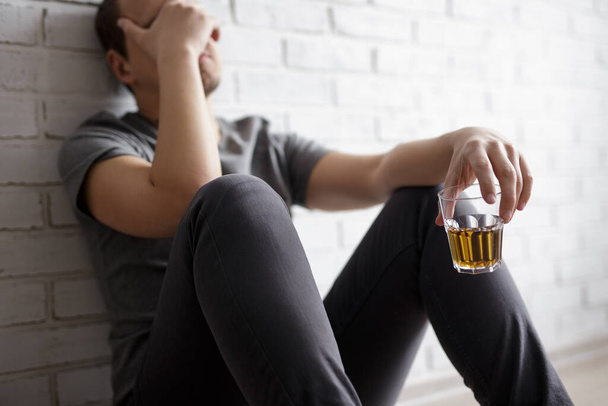 young man suffering from alcoholism, guy sitting with glass of whiskey - Photo, Image