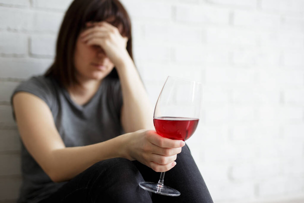 female alcoholism, relationship, divorce and depression concept - stressed woman crying and drinking wine at home - 写真・画像
