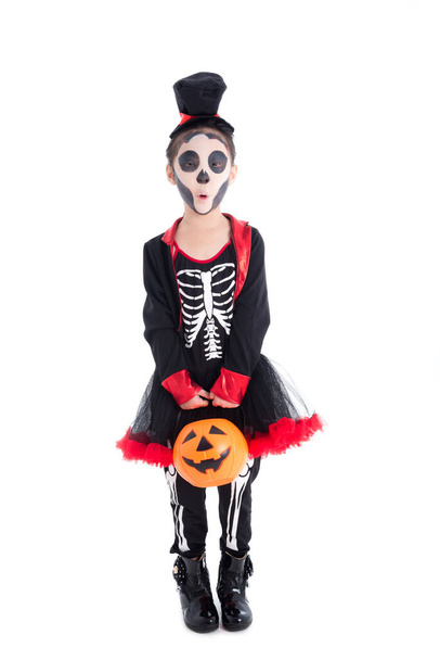 Full length of asian girl in halloween skeleton costume holding pumpkin bucket standing isolated over white background . - Photo, Image