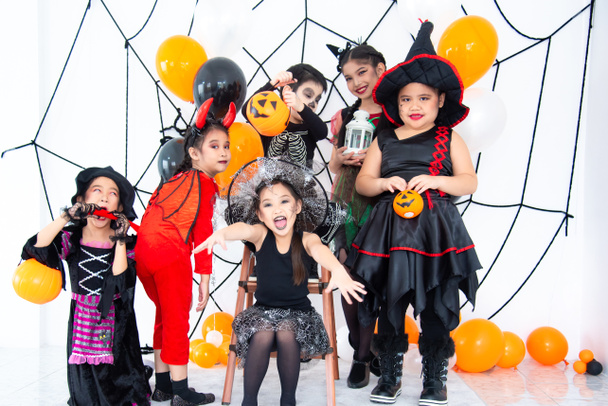 ハロウィンの衣装を着たアジアの子供たちのグループは、自宅でハロウィンパーティーを構成しています. - 写真・画像