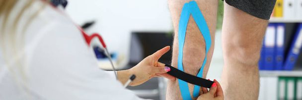 Doctor glues an elastic tape to patients leg - Фото, зображення