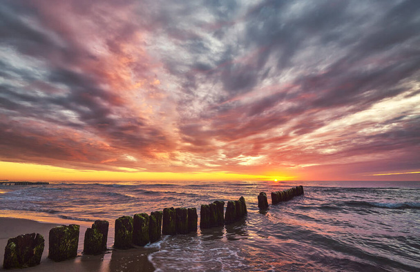 Scenic sunset over the sea with an old wooden breakwater. - Photo, Image