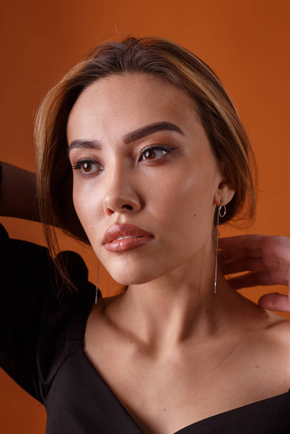 elegáns modell visel fekete ruha mély nyakkivágás pózol narancs háttér - Fotó, kép