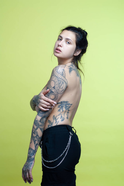 joven hermosa mujer con tatuaje posando desnuda en estudio - Foto, Imagen