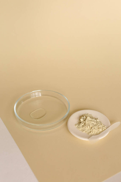 Poudre d'argile et eau dans un bocal en verre sur fond beige. - Photo, image