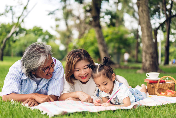 Portrait of happy grandfather with grandmother and little cute girl enjoy relax in summer park.Young girl with their laughing grandparents smiling together.Family and togetherness - Photo, Image