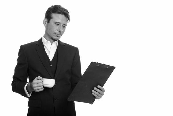 Studioaufnahme eines gutaussehenden Geschäftsmannes mit Bartstoppeln im Anzug isoliert vor weißem Hintergrund in schwarz-weiß - Foto, Bild