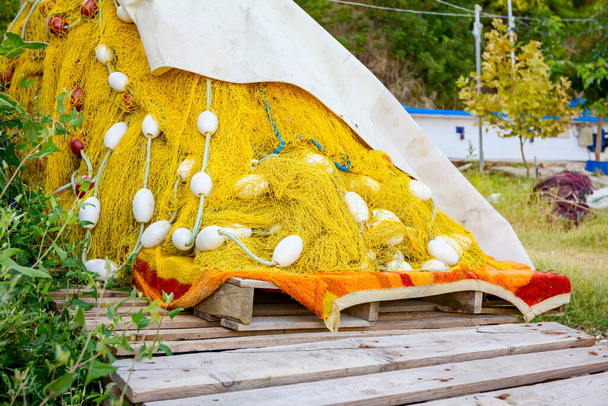 Pile of commercial fishing net on the wooden pallet at the sandy beach. - Photo, Image