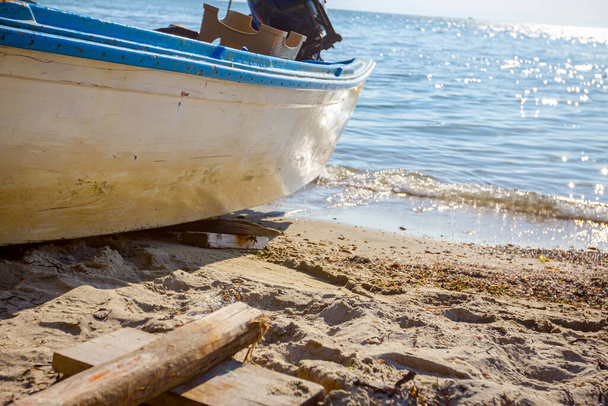 Pequeño barco de pesca blanco está acoplado en seco, retirado en la playa, costa. - Foto, imagen