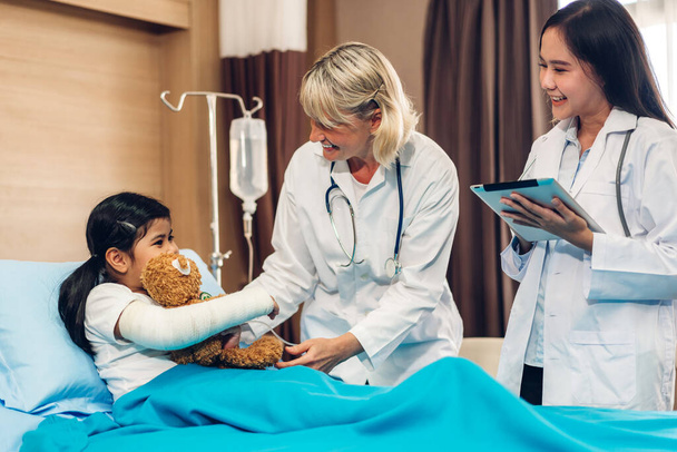 Usmívající se žena lékař služba pomoci podpořit diskusi a poradenství mluvit s malou holčičkou pacient dát medvídek a zkontrolovat informace v nemocnici - Fotografie, Obrázek