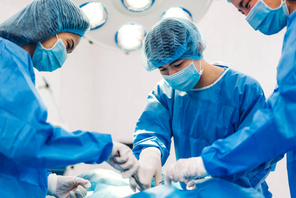 Professional anesthesiologist doctor medical team and assistant preparing patient to gynecological surgery performing operating with surgery equipment in modern hospital operation emergency room - Photo, Image