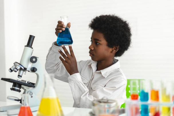 African american cute little boy student child learning research and doing a chemical experiment while making analyzing and mixing  liquid in glass at science class on the table.Education - Zdjęcie, obraz