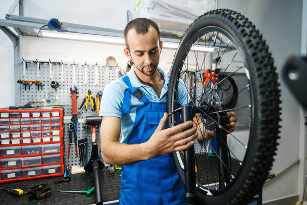 Montaż rowerów w warsztacie, człowiek zakładający łańcuch. Mechanik w mundurze naprawić problemy z rowerem, profesjonalny serwis naprawy rowerów - Zdjęcie, obraz