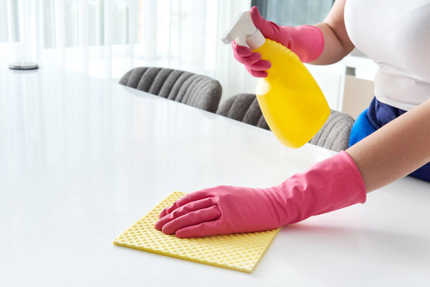 Καθαρισμός σπίτι τραπέζι απολύμανση επιφάνεια τραπέζι κουζίνα με απολυμαντικό σπρέι επιφάνειες πλύσης μπουκάλι με πετσέτα και γάντια. COVID-19 απολύμανση στο εσωτερικό. - Φωτογραφία, εικόνα