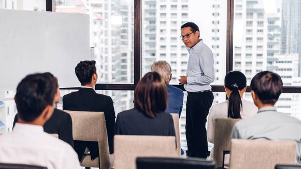 Бизнесмен, стоящий перед группой людей на семинаре консультационных совещаний в зале или помещении семинара. - Фото, изображение