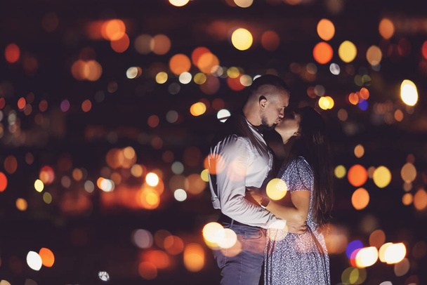 夜空の星、ボケのライトと夜の都市の背景にロマンチックな恋人カップル - 写真・画像