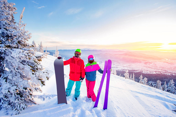 Milující pár snowboardista a lyžař se drží za ruce na pozadí hor v zimním lese, Sunlight. Koncepce lyžařského střediska - Fotografie, Obrázek