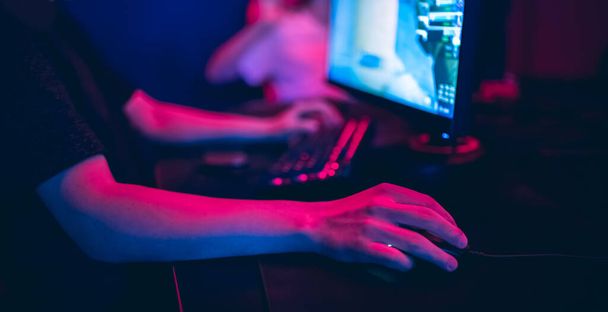 Профессиональный геймер, играющий в онлайн игры турниры ПК компьютер с наушниками, размытый красный и синий фон - Фото, изображение