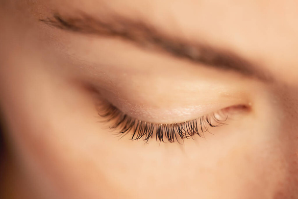 Eyelash extension procedure. Beautiful female eyes with long lashes closeup - Фото, изображение