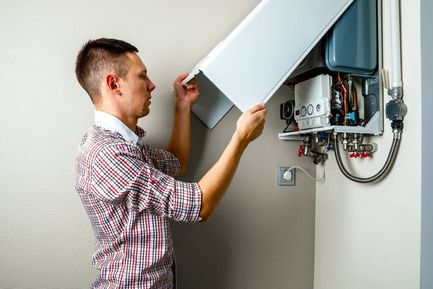 Plumber attaches Trying To Fix the Problem with the Residential Heating Equipment. Repair of a gas boiler - Zdjęcie, obraz