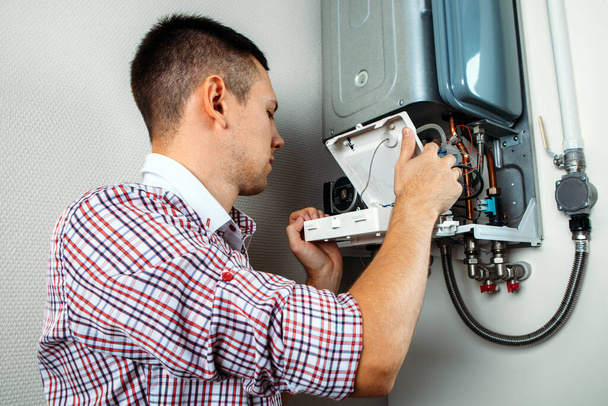 Plumber attaches Trying To Fix the Problem with the Residential Heating Equipment. Repair of a gas boiler - Fotó, kép