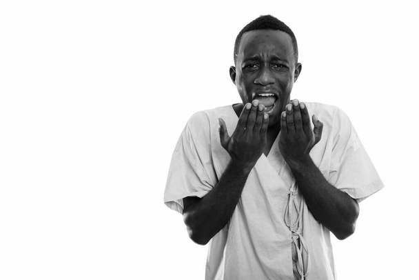 Studio shot of young African man as hospital patient isolated against white background in black and white - 写真・画像