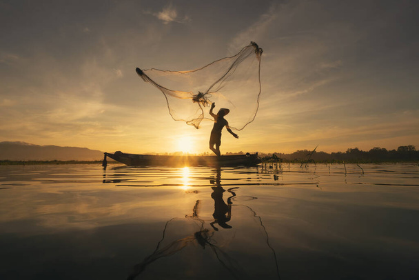 Silhouette Pêcheur jetant ou jetant un filet pour attraper des poissons d'eau douce dans le lac ou la rivière de la nature avec réflexion le matin en Asie en Thaïlande. Les gens. - Photo, image