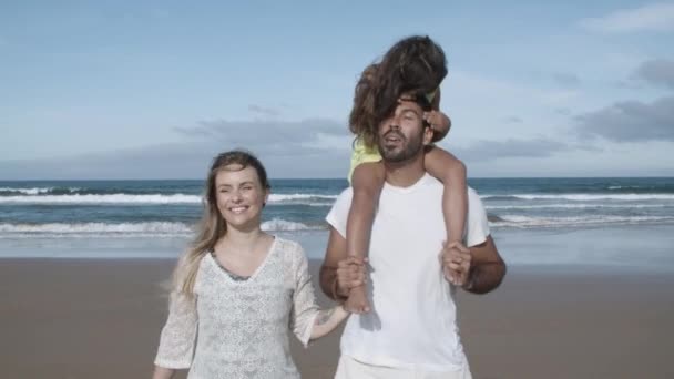 幸せな両親と子供がビーチを歩く - 映像、動画