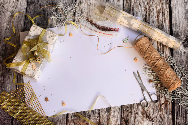  Elegante diseño plano con espacio para escribir, preparándose para Navidad, con caja de regalo, tijeras, copo de nieve sobre fondo de madera.  - Foto, Imagen