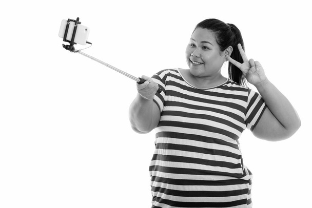 Studio shot van jonge mooie overgewicht Aziatische vrouw geïsoleerd tegen witte achtergrond in zwart-wit - Foto, afbeelding