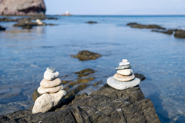 岩の多いビーチの岩の上に白い小石のバランスのピラミッド - 写真・画像