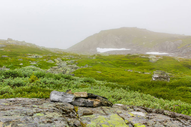 Big rocks and cliffs with fog and clouds on Veslehdn Veslehorn mountain in Hemsedal Norway. - Photo, Image