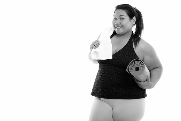Studioaufnahme einer jungen schönen, übergewichtigen Asiatin, bereit für das Fitnessstudio, isoliert vor weißem Hintergrund in schwarz-weiß - Foto, Bild