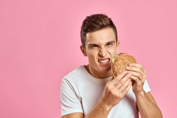 man with big hamburger on pink background calories fast food cropped view Copy Space close-up - 写真・画像