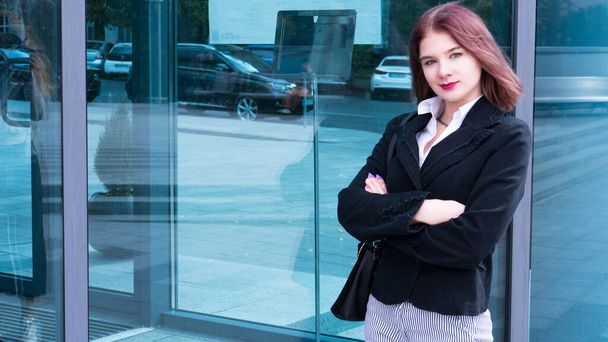 Outdoor portrait of young beautiful business woman on street near office. Attractive red hair office lady standing outside in formal suit.Fashion hostess woman with bob haircut and copy space - Photo, image