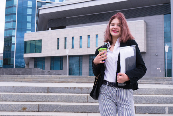 Outdoor portrait of young beautiful business woman on street near office. Attractive red hair office lady standing outside in formal suit.Fashion hostess woman with bob haircut and copy space - Photo, image