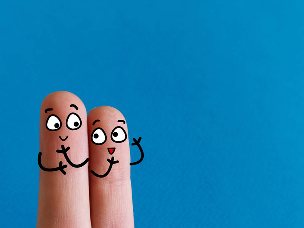 Zwei Finger sind als zwei Personen dekoriert. Sie reden miteinander. - Foto, Bild