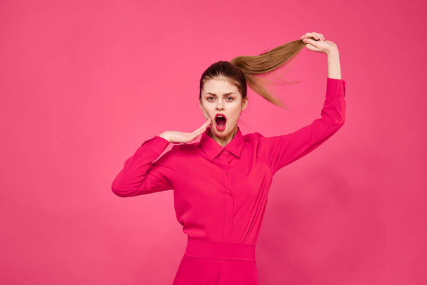 Portrait of a red-haired woman in bright clothes on a pink background cropped view of gesturing with her hands - Foto, afbeelding