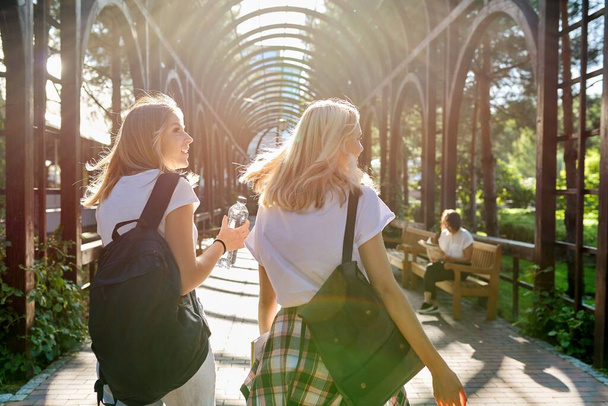Two happy smiling talking girls teenagers students walking together - Фото, зображення
