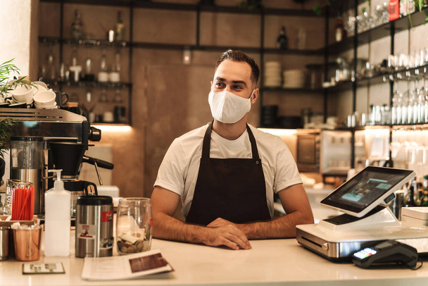 Barista with face mask in coffee shop, lockdown, quarantine, coronavirus, back to normal concept - Фото, изображение