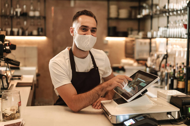 Barista with face mask in coffee shop, lockdown, quarantine, coronavirus, back to normal concept - Фото, зображення