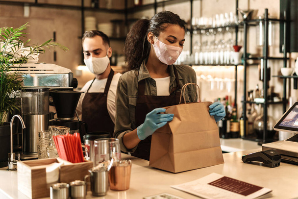 Coffee shop owners with face masks, lockdown, quarantine, coronavirus, back to normal concept, packing takeaway order - Photo, Image
