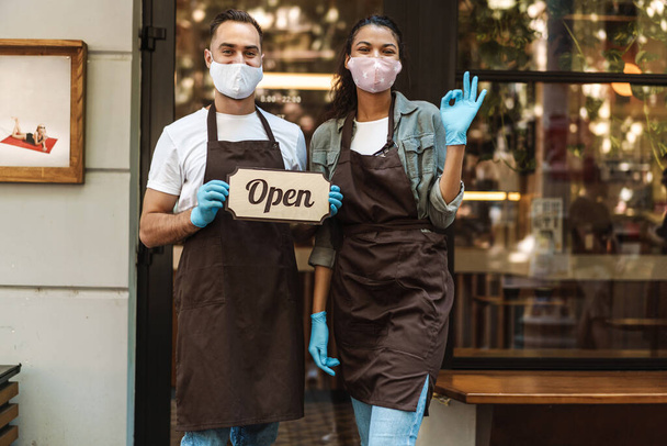 Man and woman coffee shop owners with face mask open after lockdown quarantine - Foto, Imagen