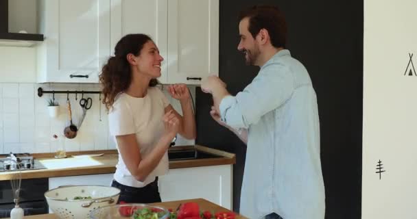 Lively married couple dancing in kitchen during breakfast preparation - Materiaali, video